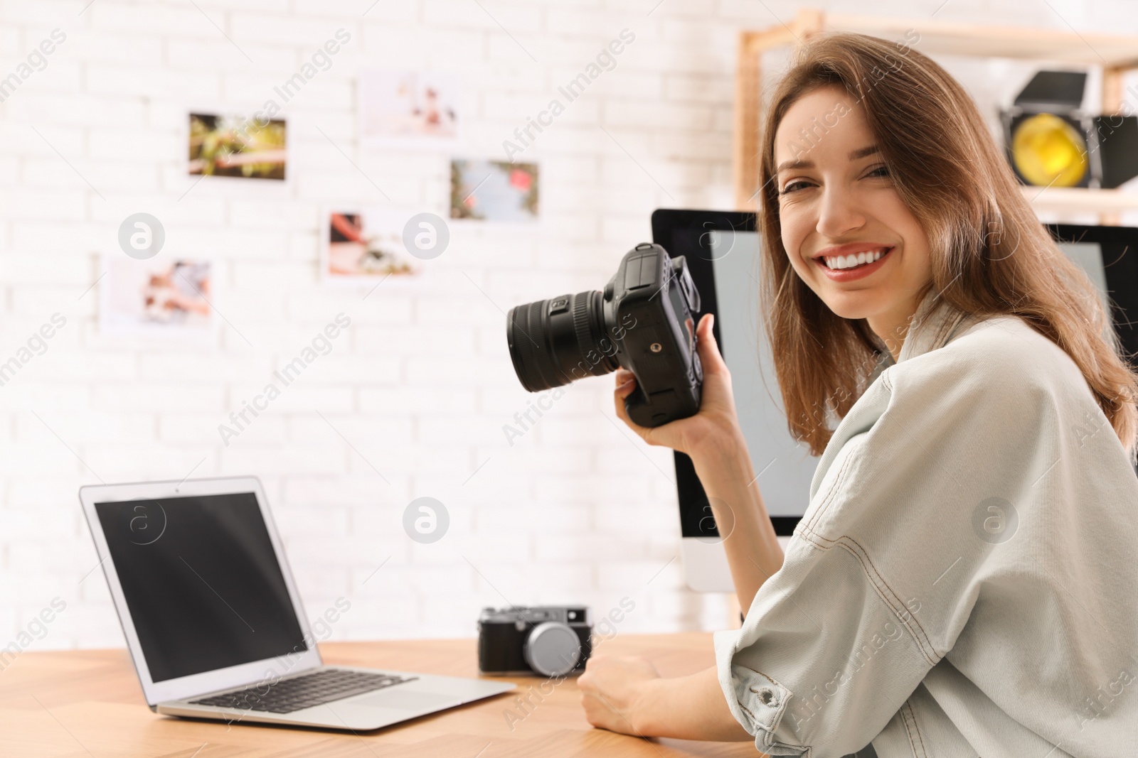 Photo of Professional photographer with camera working at table in office