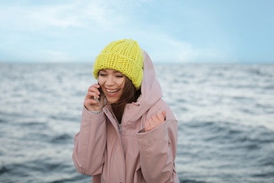 Photo of Young woman talking on mobile phone near sea