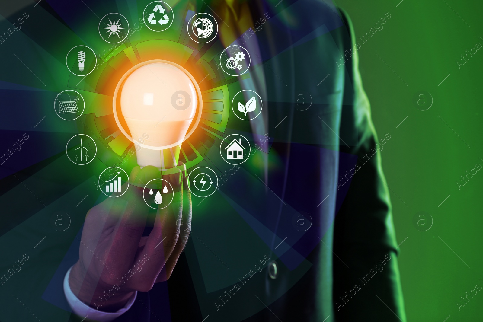 Image of Energy efficiency concept. Man holding light bulb surrounded by icons, closeup