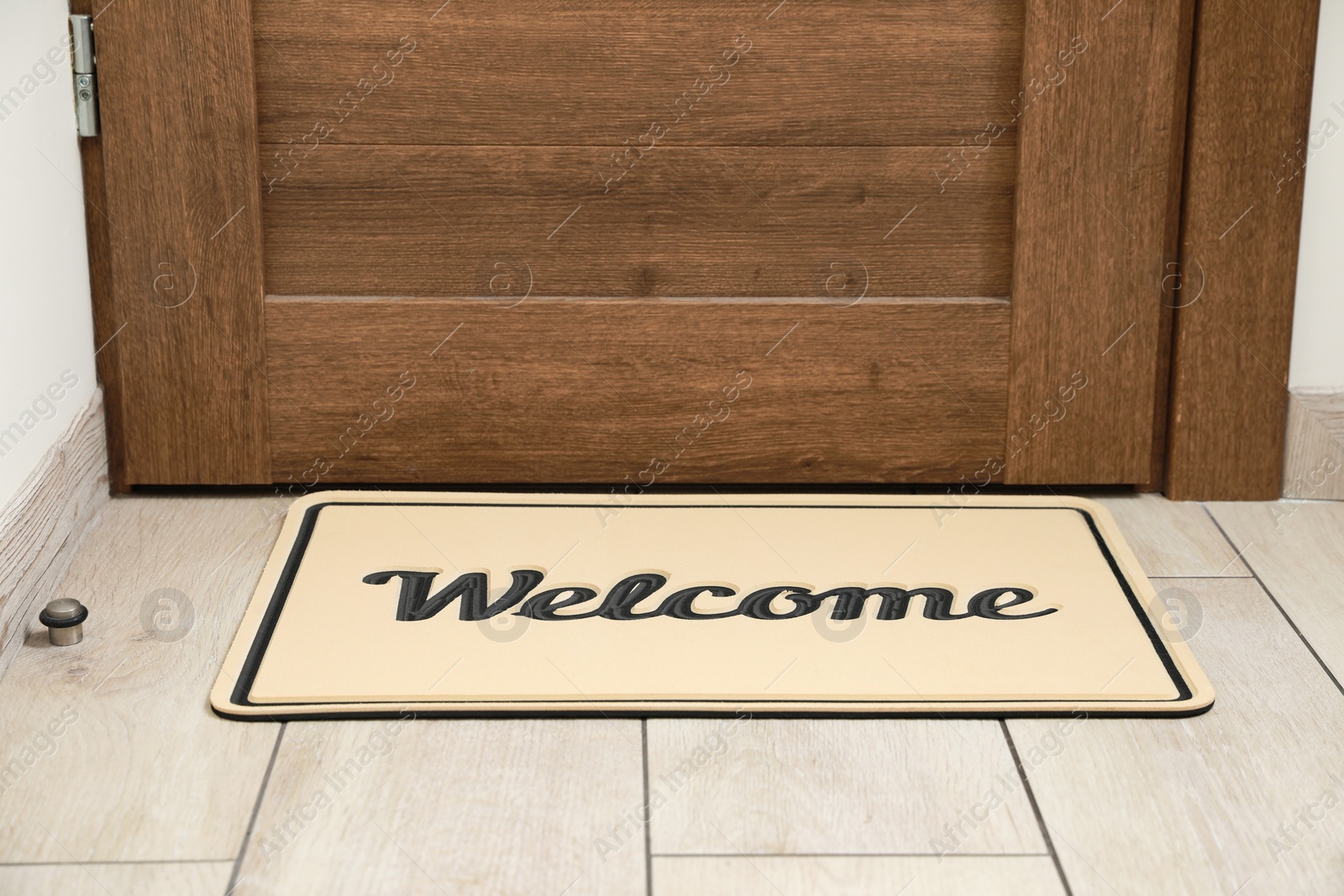 Photo of Beautiful beige doormat with word Welcome on floor near entrance