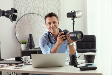 Photo of Portrait of photo blogger with camera and laptop at home