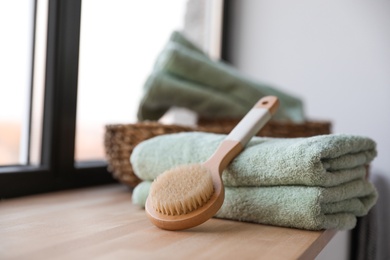 Photo of Clean soft towels and shower brush on windowsill in bathroom