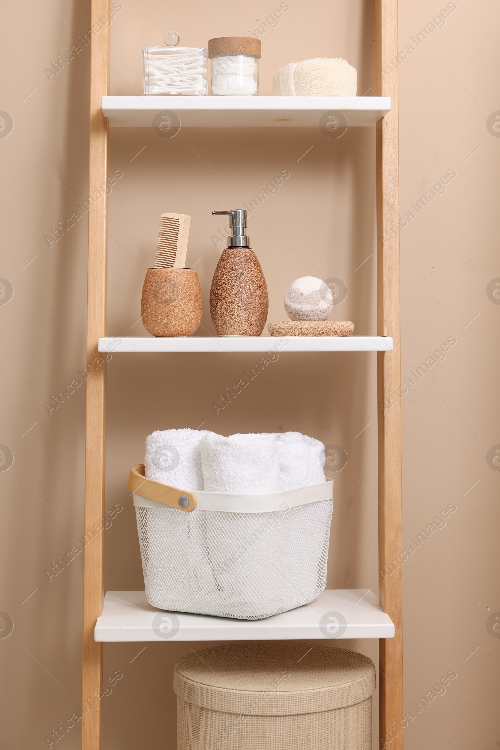 Photo of Different bath accessories and personal care products on shelving unit near beige wall