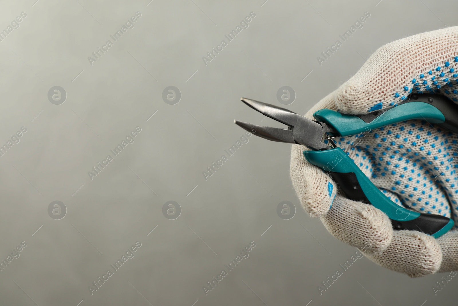 Photo of Man with bent nose pliers on grey background, closeup. Space for text