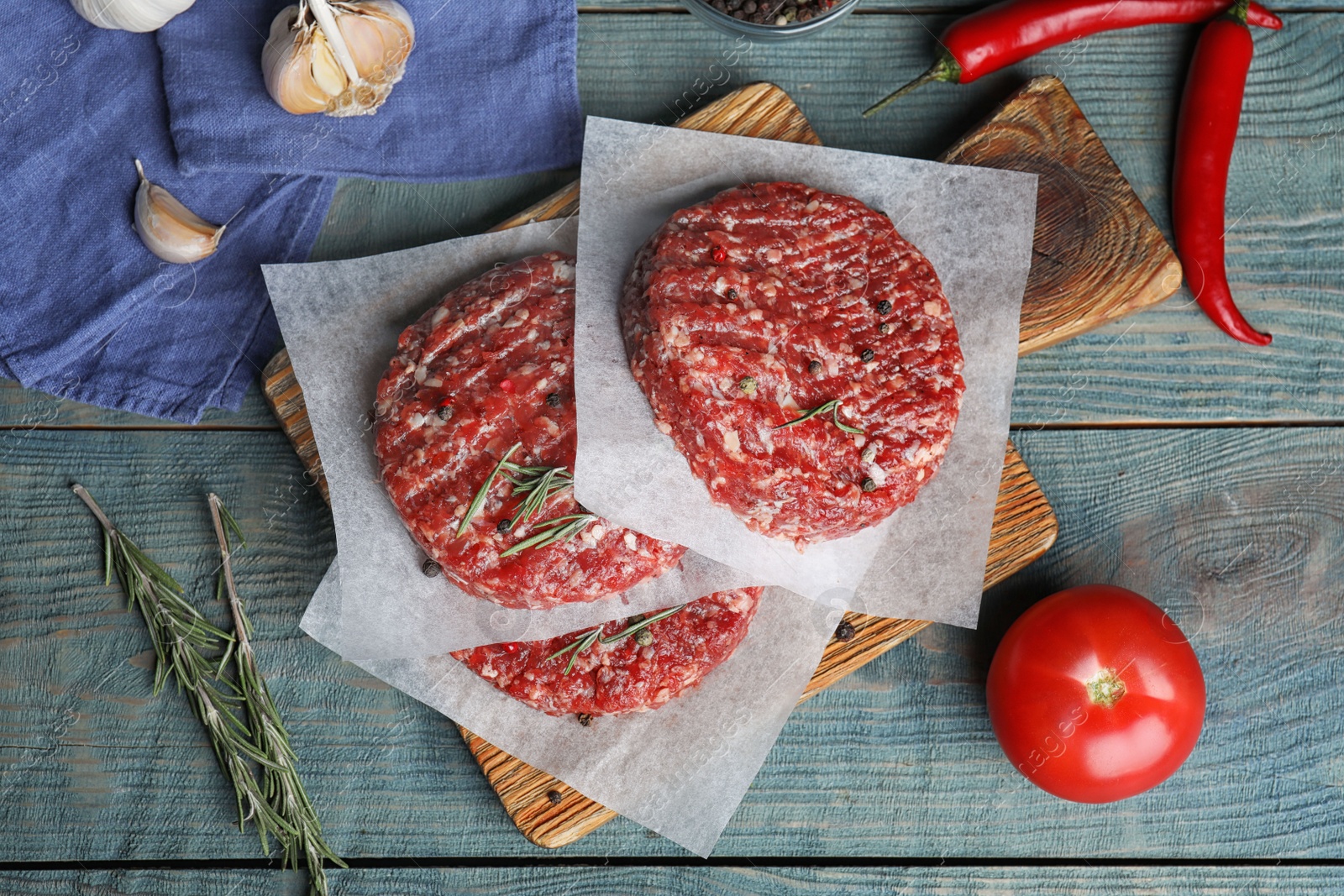 Photo of Flat lay composition with raw meat cutlets for burger on blue wooden table