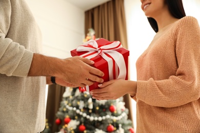 Photo of Happy couple with Christmas gift at home, closeup