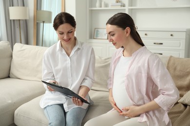 Doula working with pregnant woman on sofa at home. Preparation for child birth