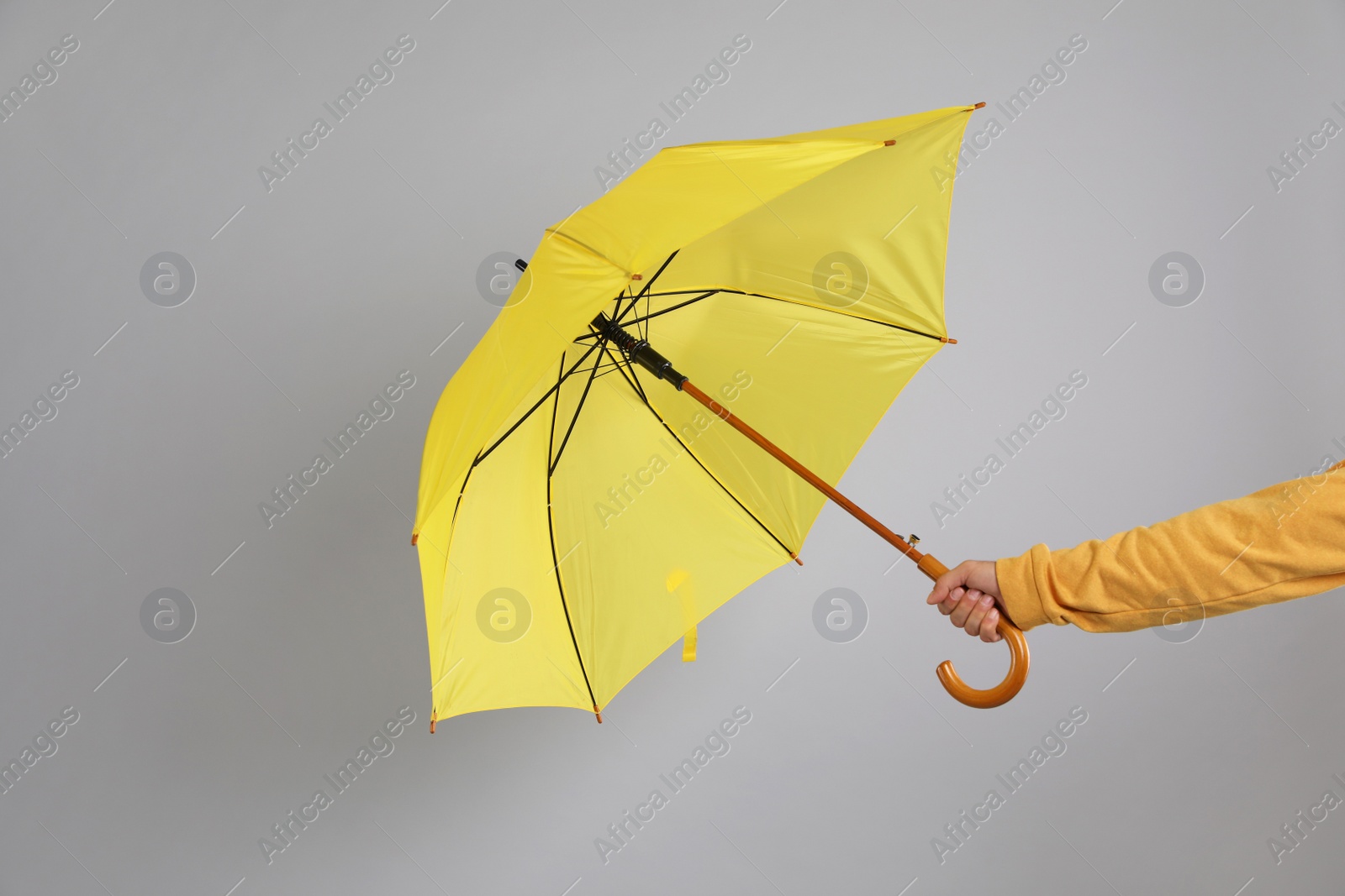 Photo of Man holding umbrella caught in gust of wind on grey background, closeup