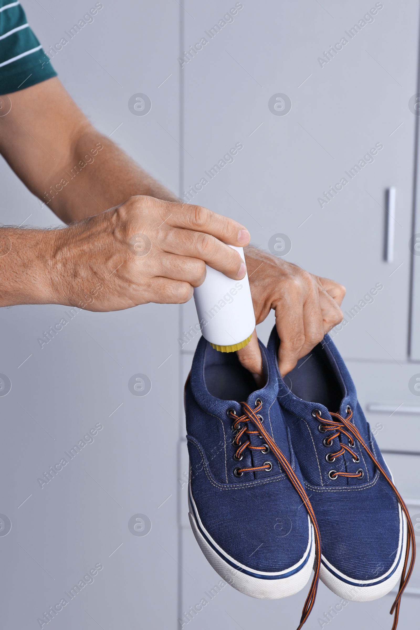 Photo of Man putting powder shoe freshener in footwear indoors, closeup