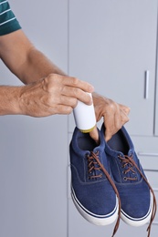Man putting powder shoe freshener in footwear indoors, closeup