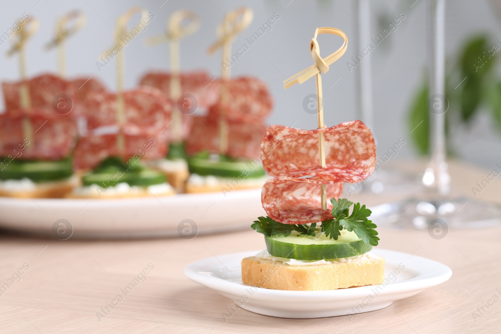 Photo of Tasty canapes with salami, cucumber and cream cheese on light table, closeup. Space for text