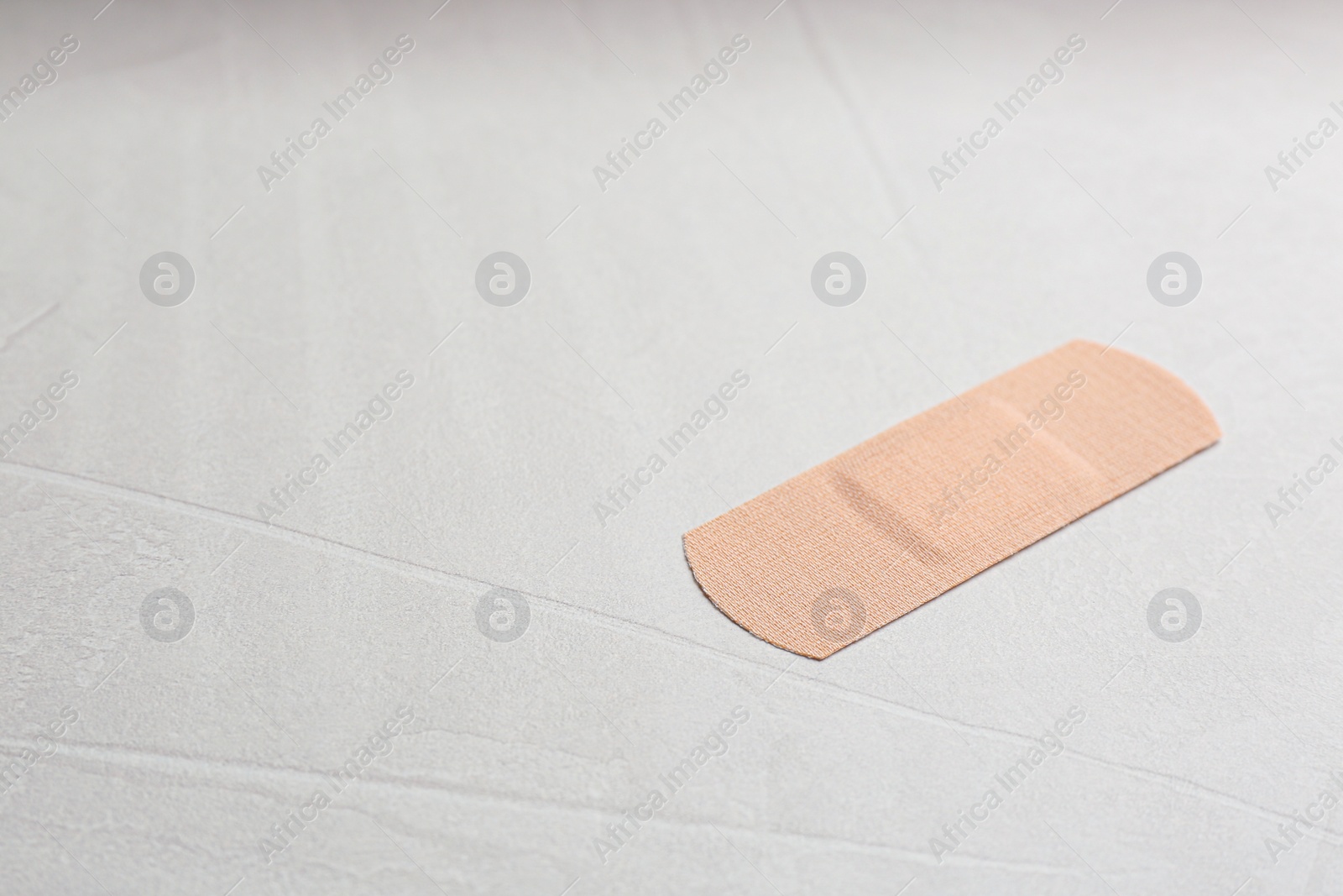 Photo of Medical sticking plaster on light stone background. Space for text