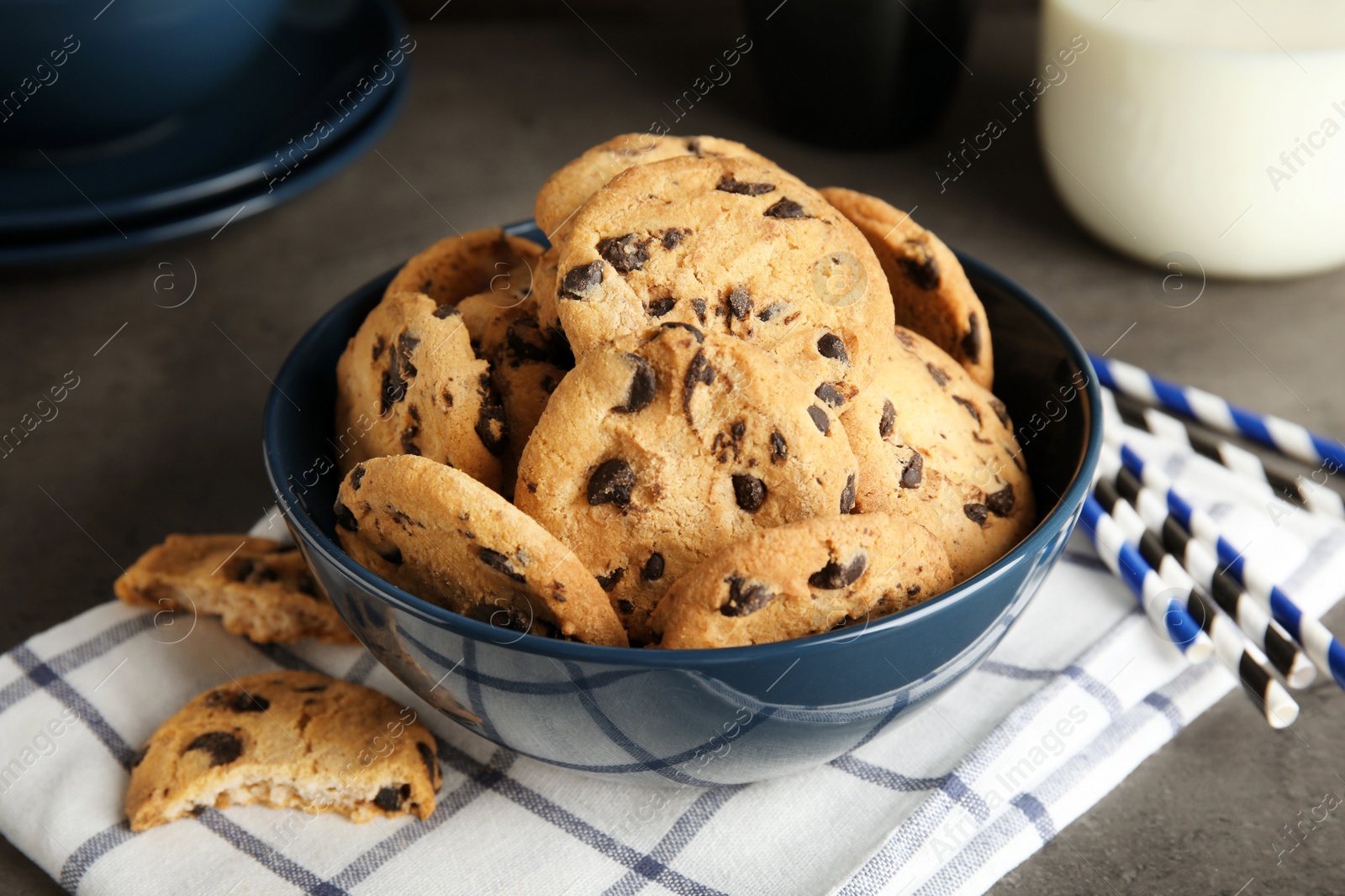 Photo of Bowl with tasty chocolate chip cookies on table
