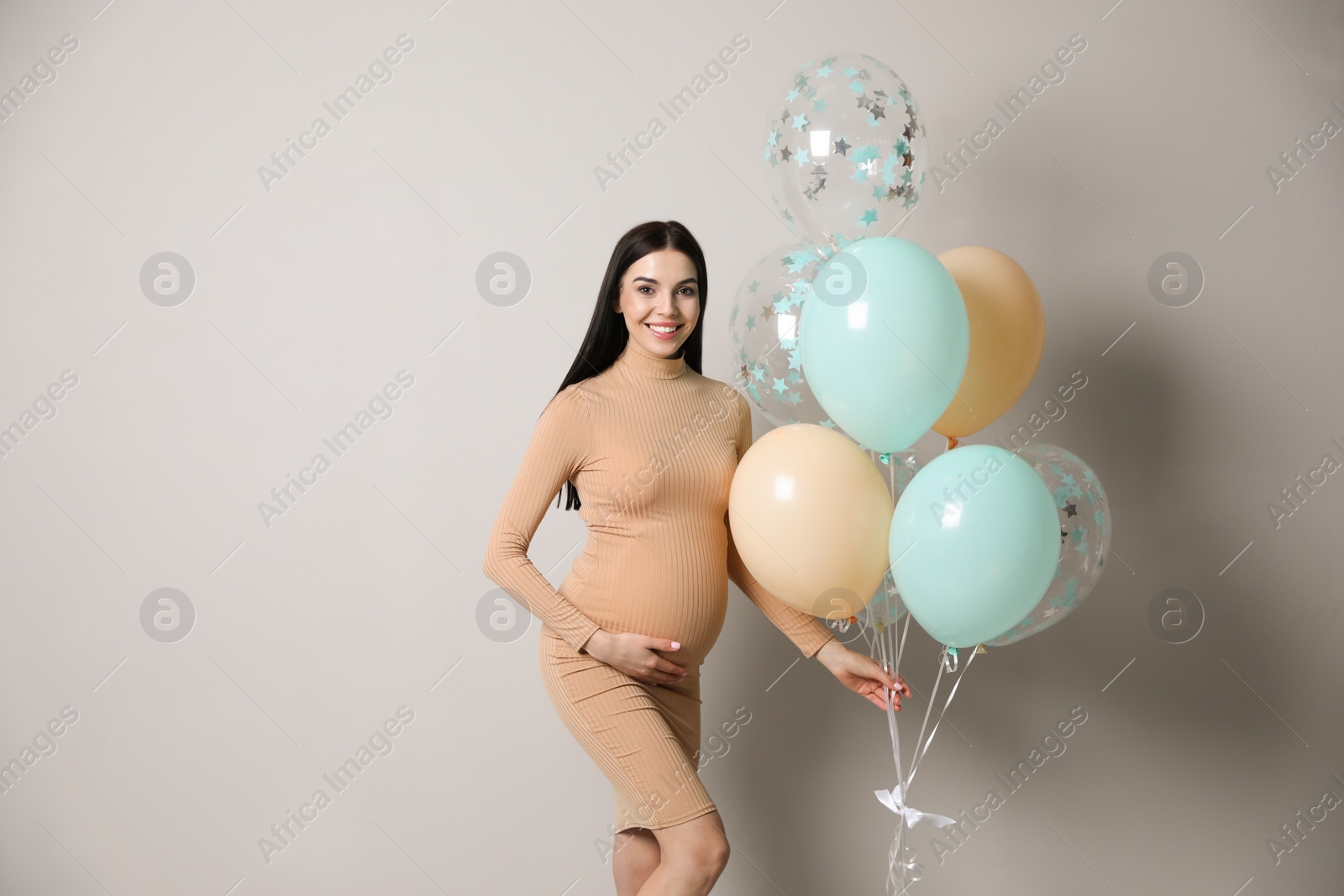 Photo of Happy pregnant woman with balloons near grey wall. Baby shower party