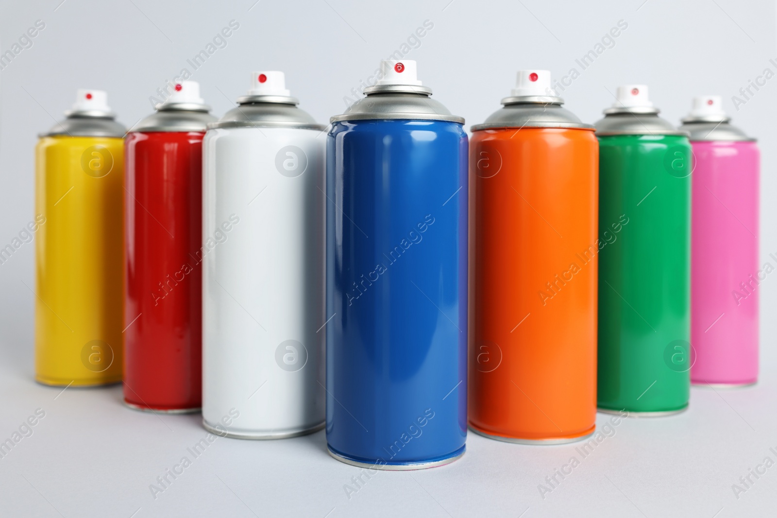 Photo of Colorful cans of spray paints on light grey background