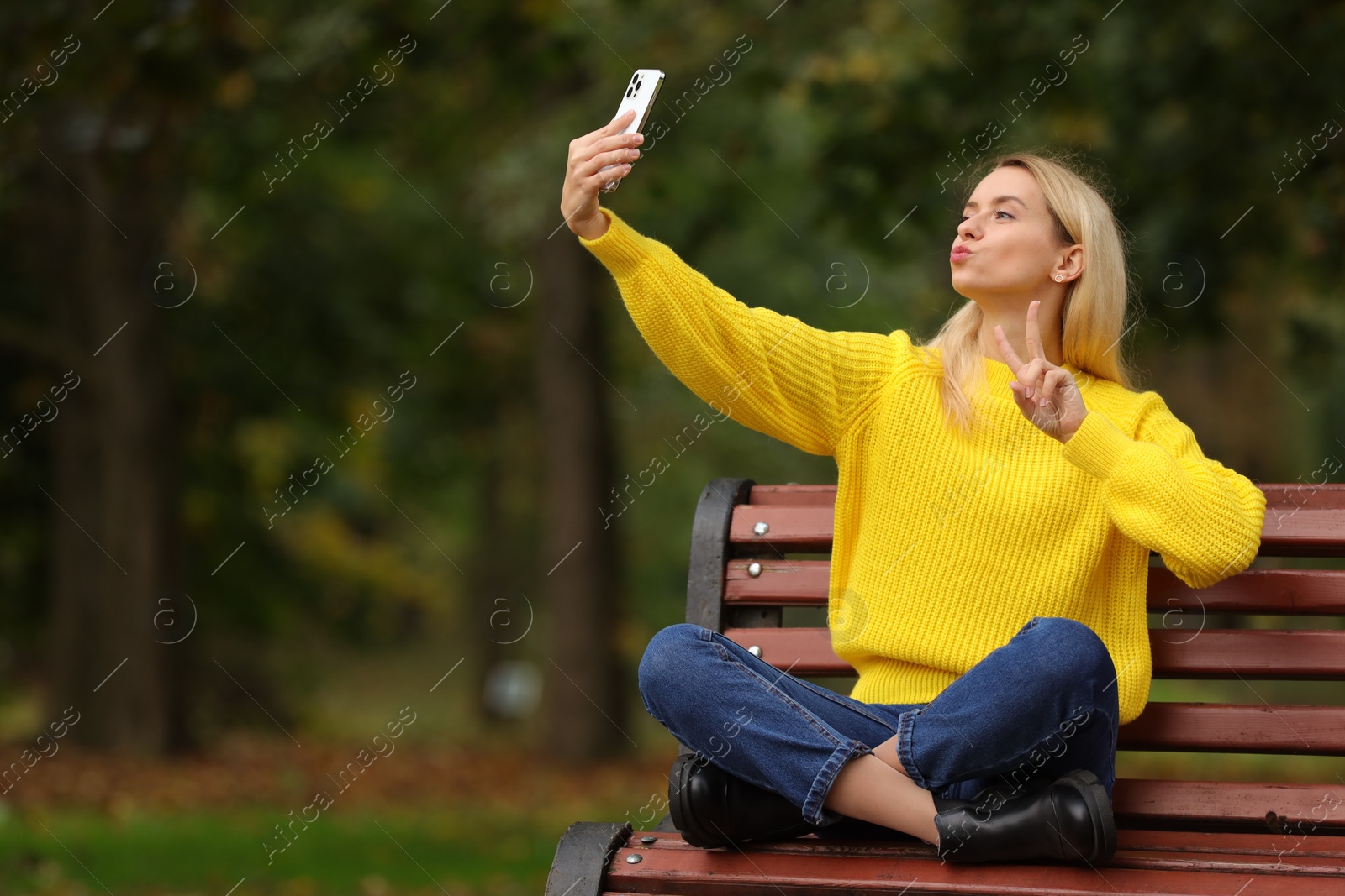 Photo of Beautiful woman taking selfie in autumn park. Space for text