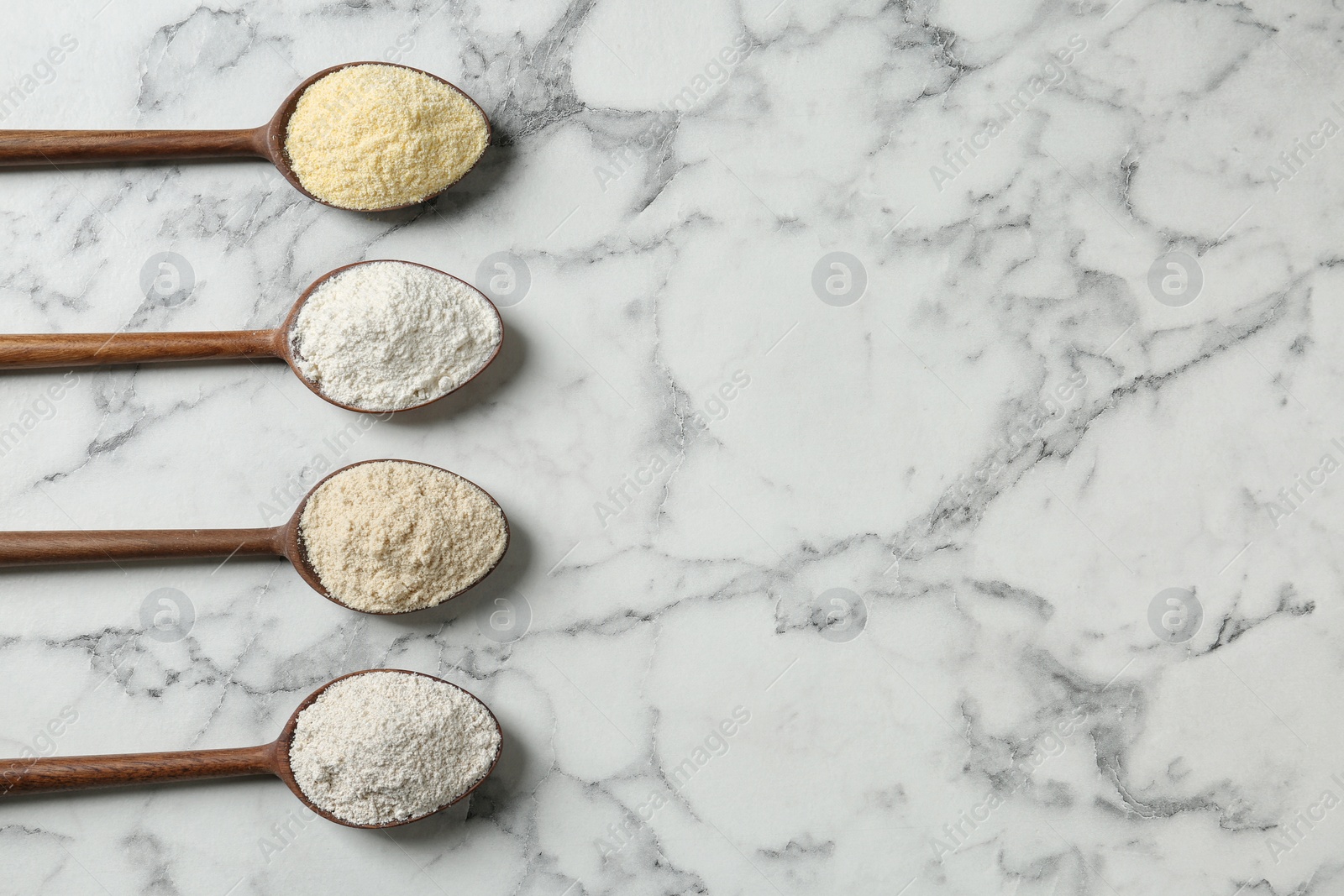 Photo of Spoons with different types of flour on marble background, top view. Space for text