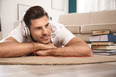 Photo of Man with headphones connected to book
on floor at home. Audiobook concept