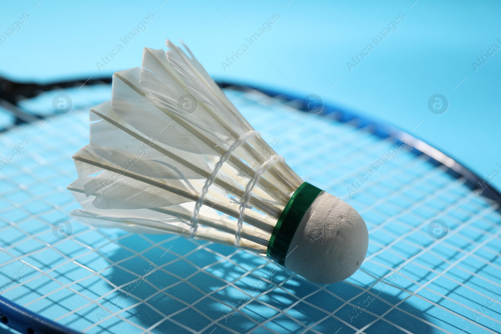 Photo of Feather badminton shuttlecock and racket on light blue background, closeup