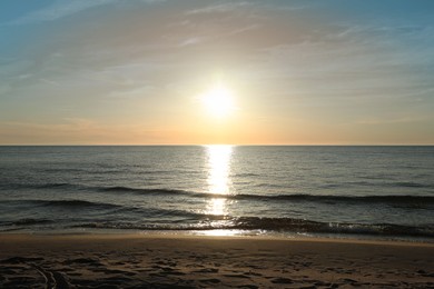 Photo of Picturesque view of sandy beach and sea at sunset