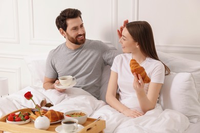 Happy couple having tasty breakfast in bed at home