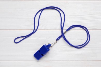 One blue whistle with cord on white wooden table, top view