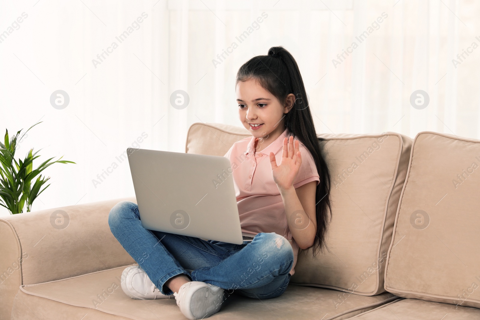 Photo of Little girl using video chat on laptop at home