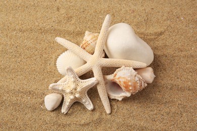 Photo of Beautiful sea stars, shells and stones on sand, above view