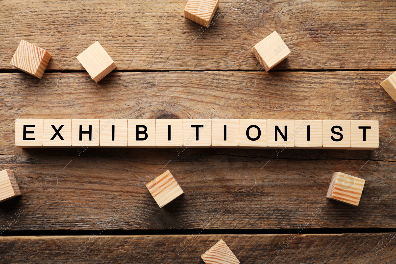 Photo of Word EXHIBITIONIST made with wooden cubes on table, flat lay