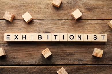Photo of Word EXHIBITIONIST made with wooden cubes on table, flat lay
