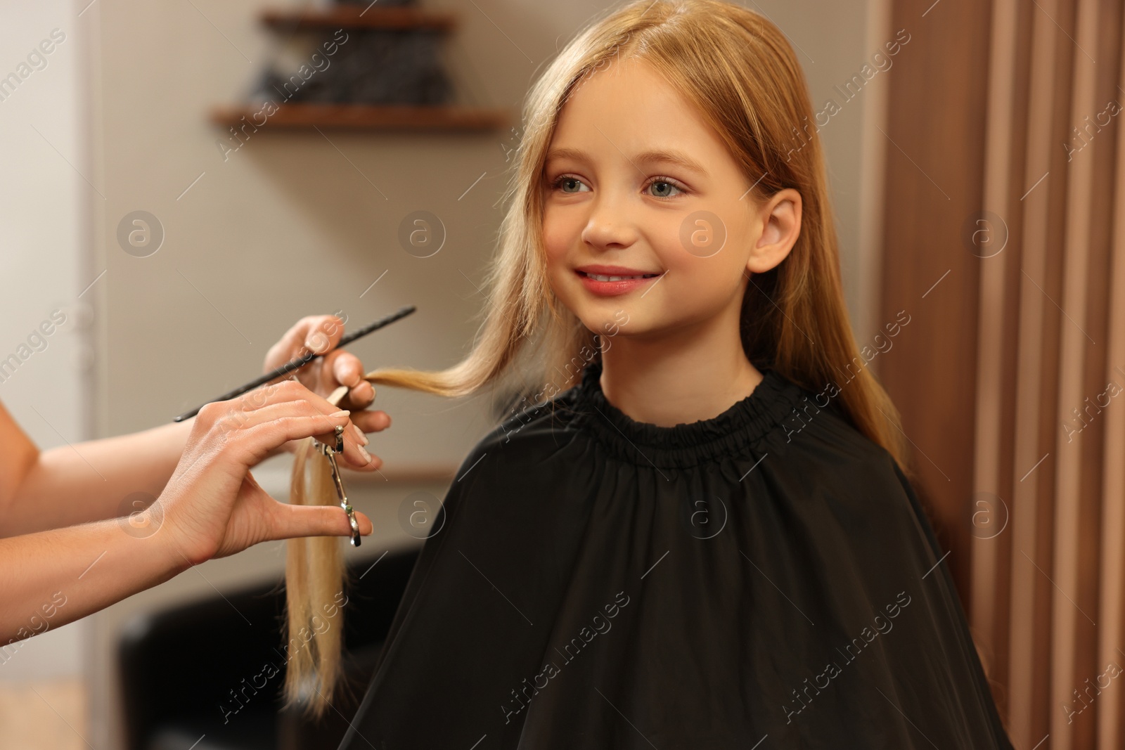 Photo of Professional hairdresser cutting girl's hair in beauty salon