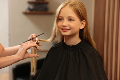 Photo of Professional hairdresser cutting girl's hair in beauty salon