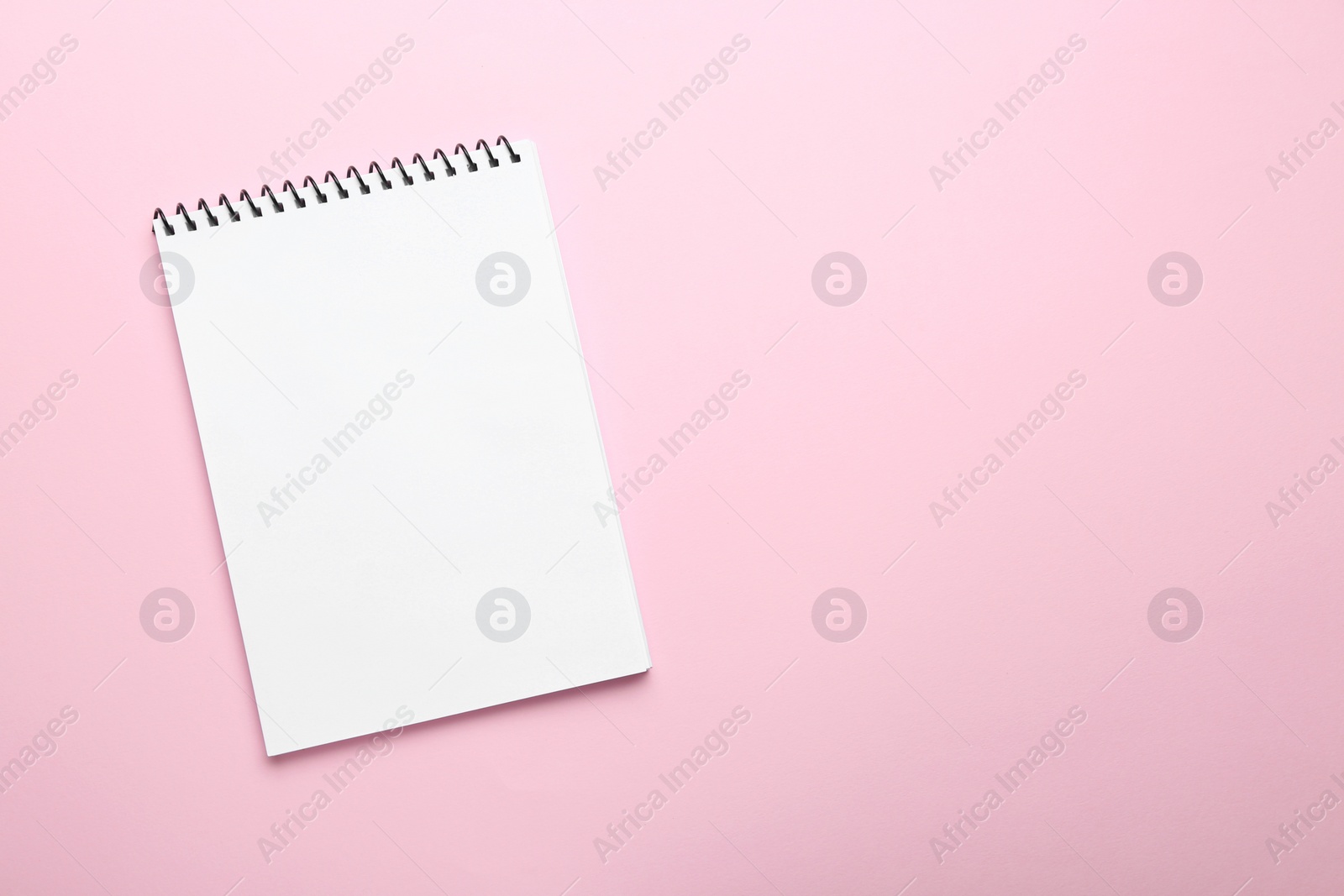 Photo of One notebook on pink background, top view. Space for text