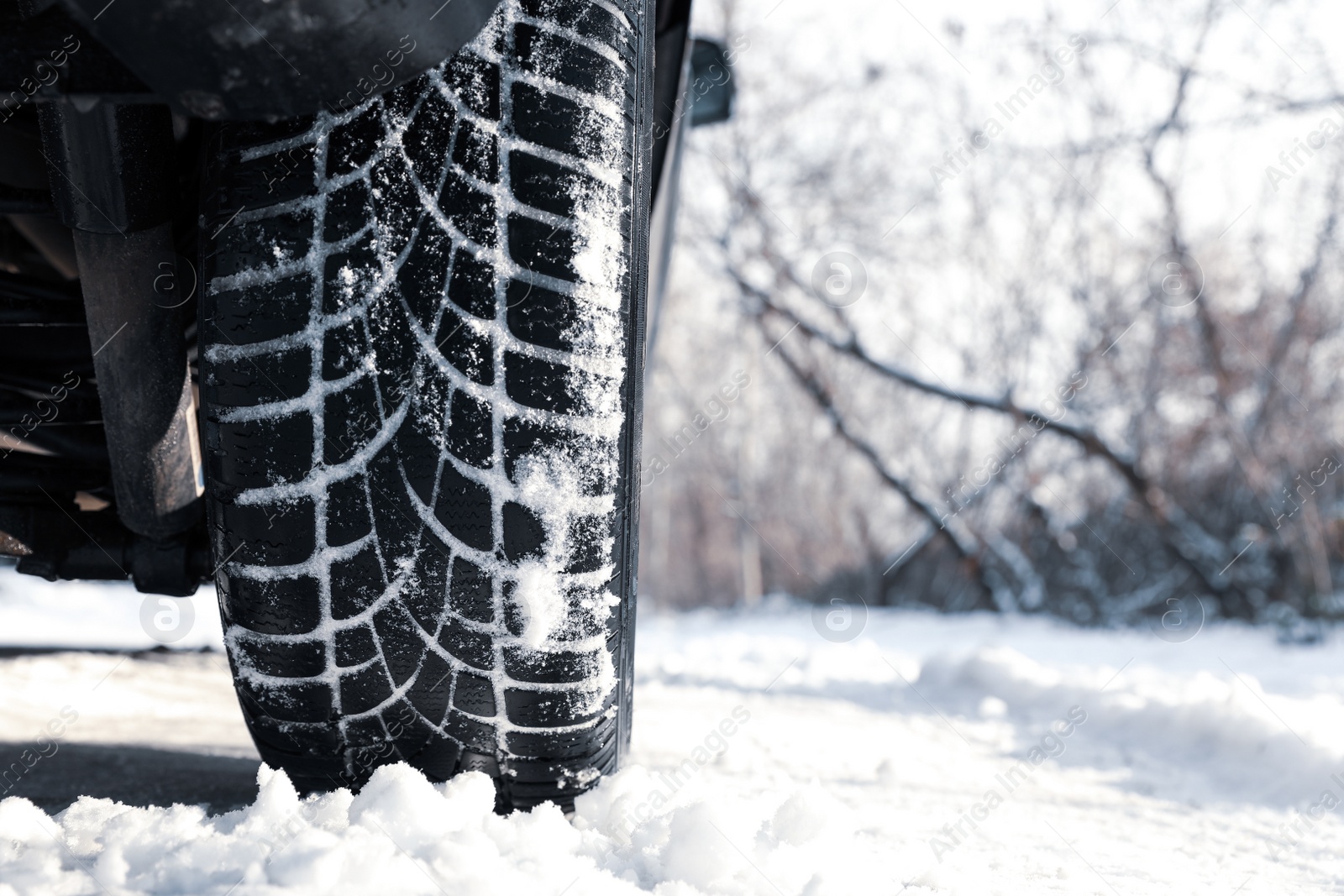 Photo of Car with winter tires on snowy road, closeup view. Space for text