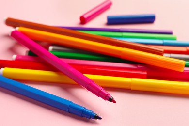 Photo of Many bright markers on pink background, closeup