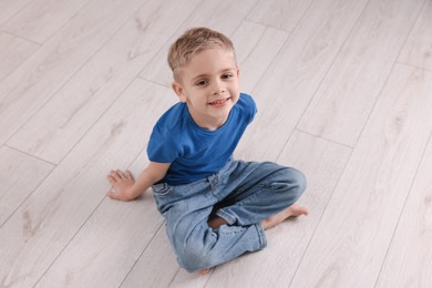 Photo of Cute little boy sitting on warm floor indoors. Heating system