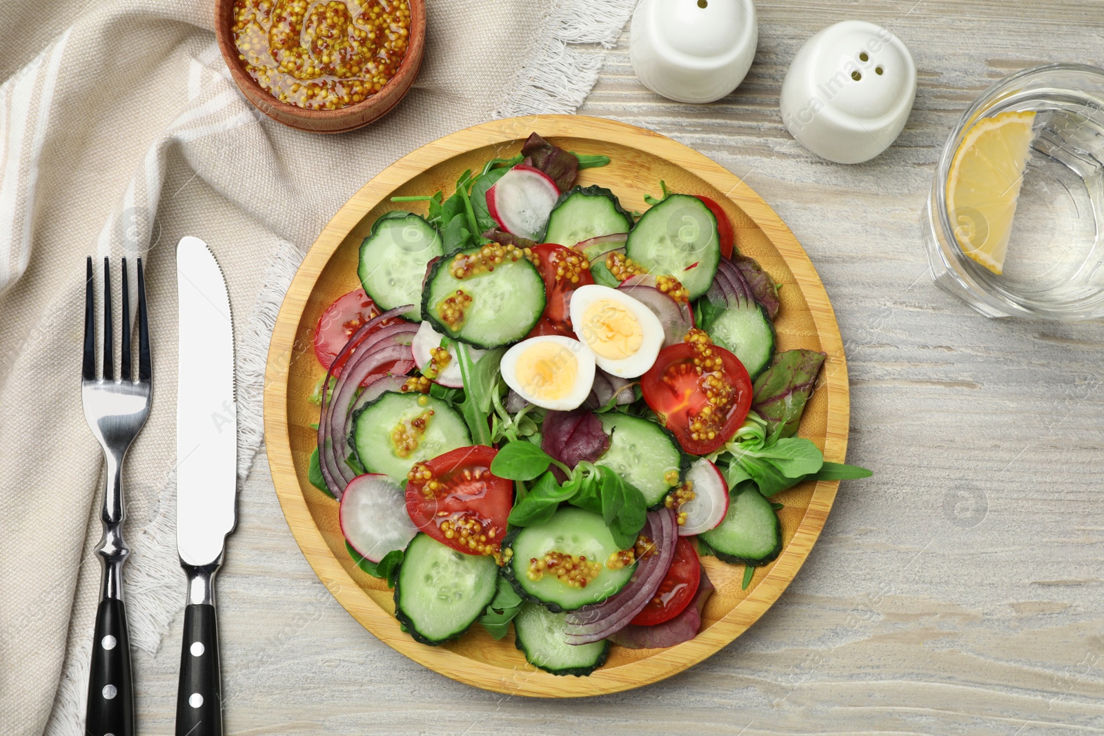 Photo of Tasty salad with vegetables and quail eggs on wooden table, flat lay