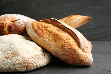 Photo of Different kinds of fresh bread on black table