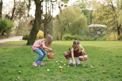 Easter celebration. Cute little girls hunting eggs outdoors