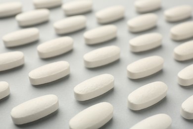 Photo of Vitamin pills on light grey background, closeup. Health supplement