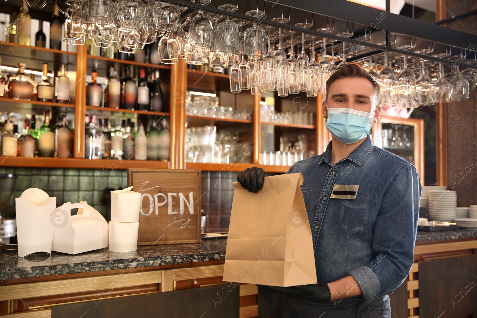 Photo of Waiter with packed takeout order in restaurant. Food service during coronavirus quarantine