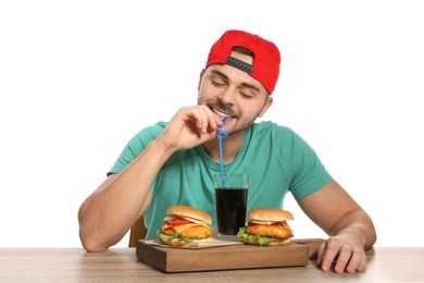Photo of Handsome man having lunch with burgers at table on white background