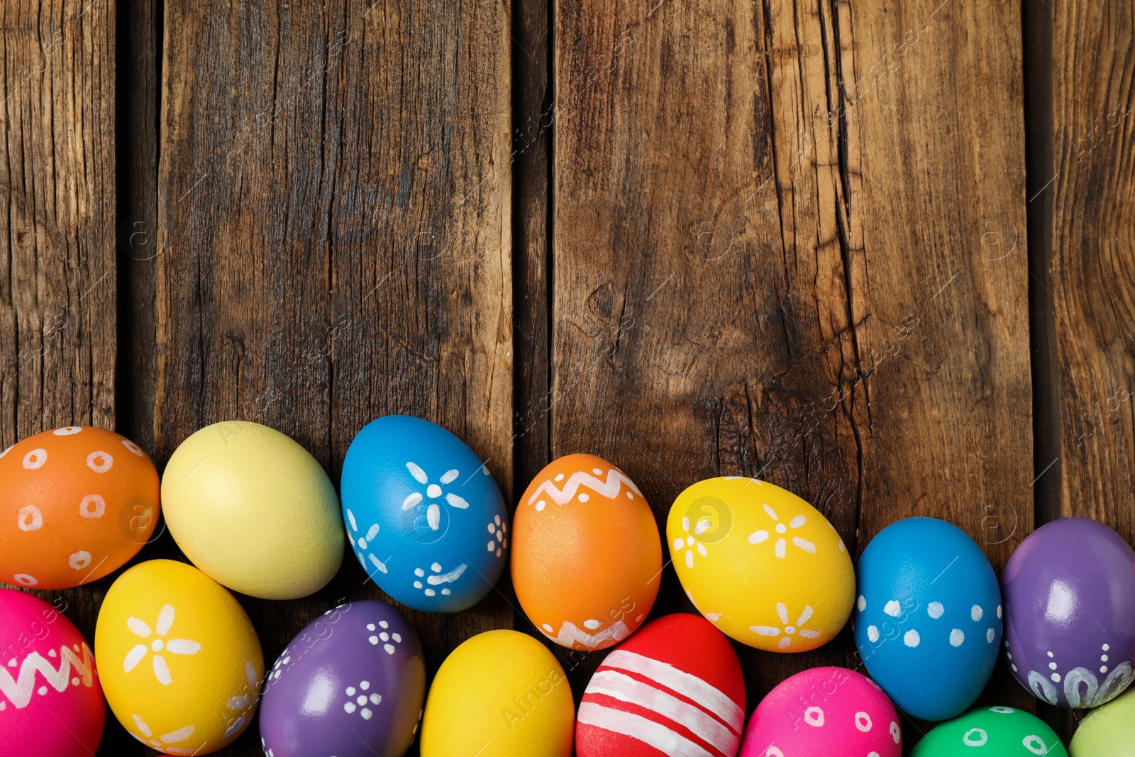 Photo of Colorful Easter eggs on wooden background, flat lay. Space for text