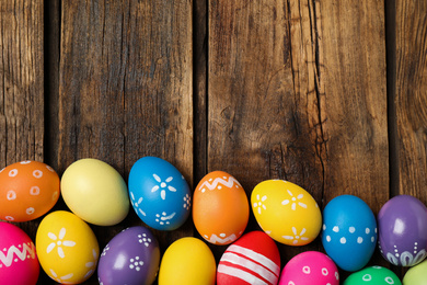 Photo of Colorful Easter eggs on wooden background, flat lay. Space for text