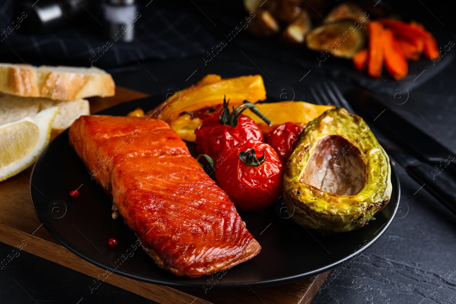 Photo of Delicious cooked salmon and vegetables on black table, closeup. Healthy meals from air fryer