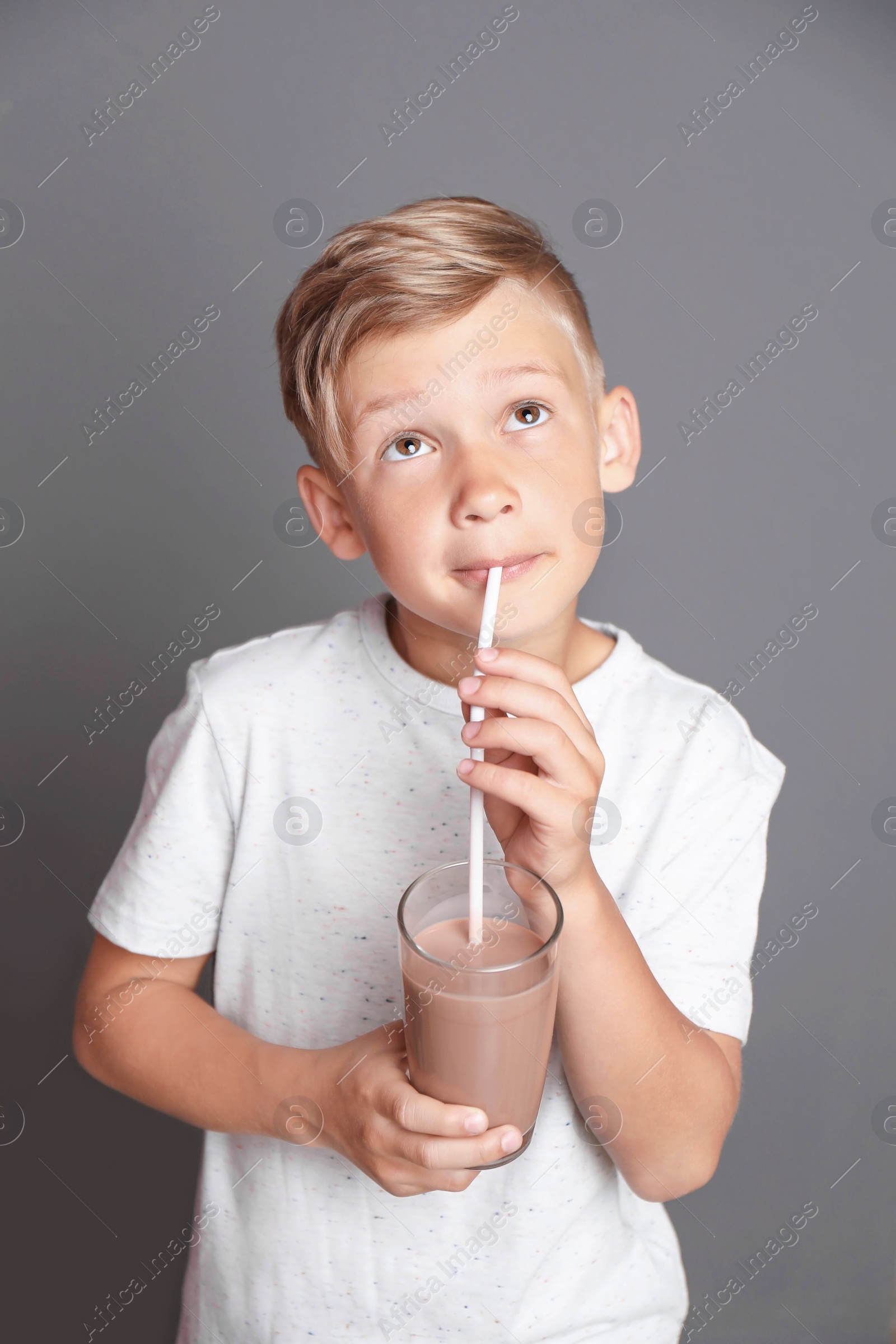 Photo of Little boy with glass of milk shake on grey background