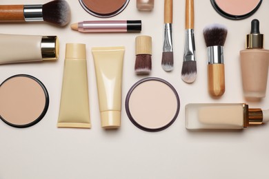 Photo of Face powders and other makeup products on beige background, flat lay