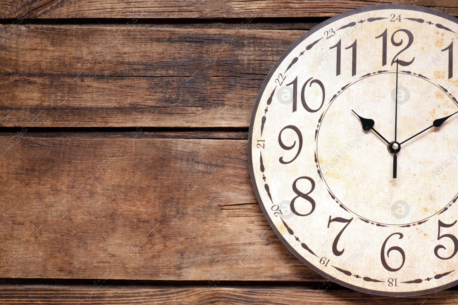 Photo of Stylish round clock on wooden table, top view with space for text. Interior element