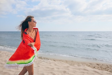 Beautiful woman with bright beach towel on seashore