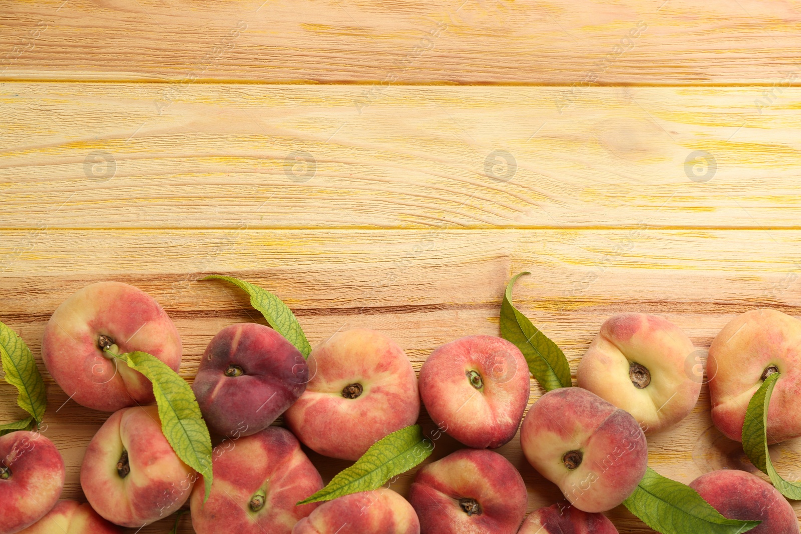 Photo of Fresh ripe donut peaches on wooden table, flat lay. Space for text
